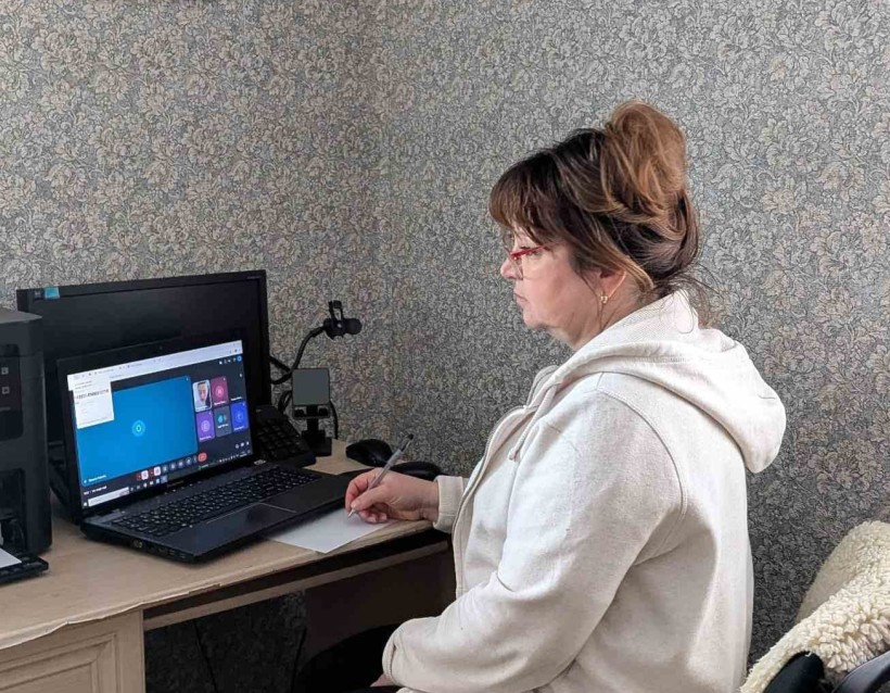 Представник військової адміністрації сидить за столом та слухає доповідача на семінарі