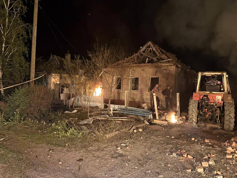Зруйнована та обгоріла будівля та трактор, який допомагає розбирати завали.