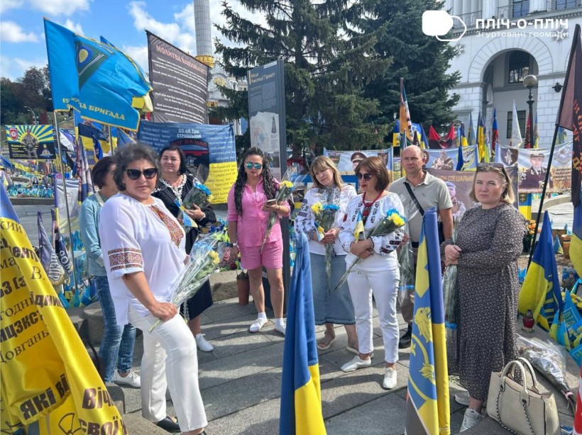 Жінки та чоловіки з квітами ідуть по алеї Слави у місті Київ.