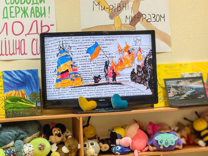 Екран монітора. Внизу на поличках знаходяться м'які іграшки різного кольору. На екрані презентація роботи. Знизу монітора серця жовтого та блакитного кольорів.