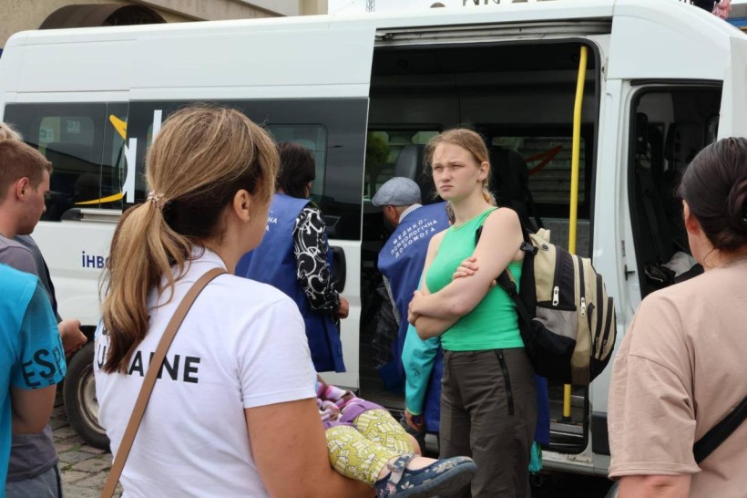 Волонтери допомагають евакуйованим громадянам завантажити речі у мікроавтобус.