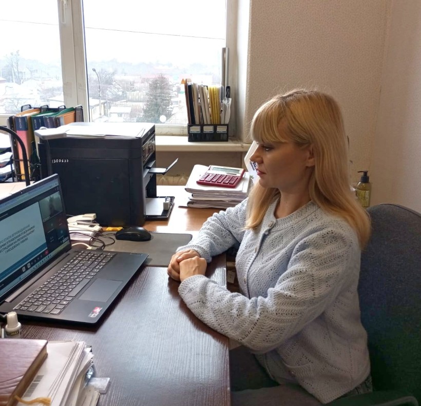 Представник військової адміністрації сидить за столом та слухає доповідача на семінарі