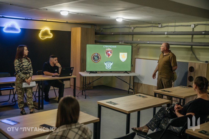 Військові проводять презентацію для молоді в межах проєкту «Наша Донеччина. Наш дім. Наша фортеця». На екрані — емблеми бойових підрозділів.