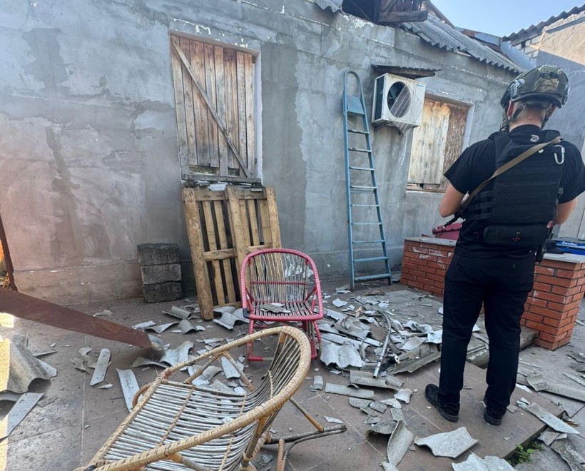 Рятувальник стоїть біля зруйнованого житла