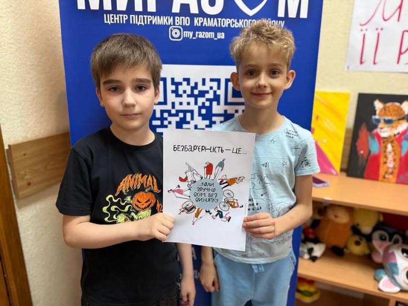 Двоє хлопчиків тримають паперовий листок з інформацією про безбар'єрність