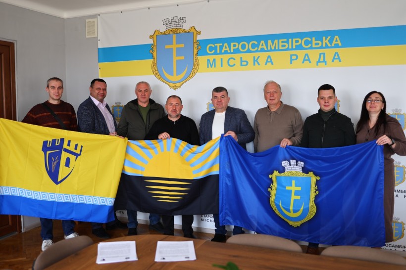 Представники громад тримають прапори Сартанської та Старосамбірської громад та прапор Донецької області