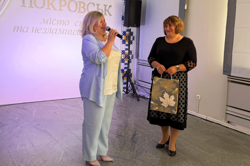 Олена Олехнович  поруч із колегою, яка тримає подарунковий пакет.