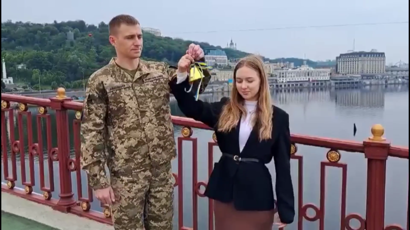 Школярка разом з військовим стоять на мосту та дають "Останній дзвоник"