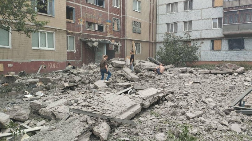 Зруйнований будинок після ворожого обстрілу та люди, які ходять біля руїн
