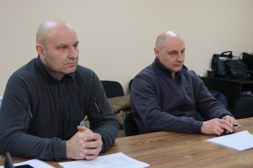 Члени наради сидять за столом.