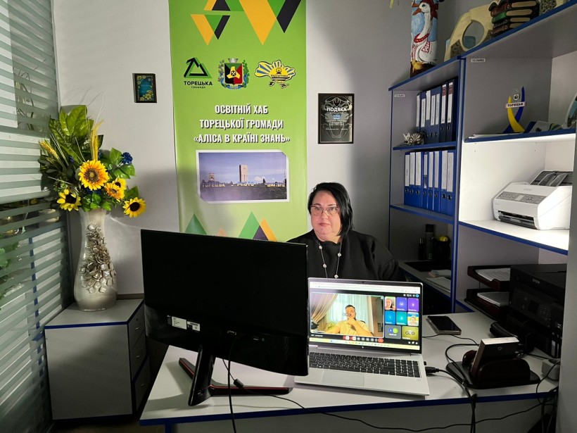 Представник військової адміністрації сидить за столом та слухає доповідача на семінарі