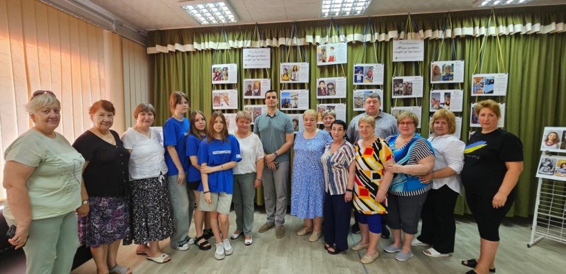 Учасники презентації фотовиставки на фоні експозиції, яка висвітлює історії жінок під час війни.