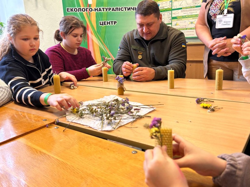 Діти разом із військовослужбовцем у процесі виготовлення свічок