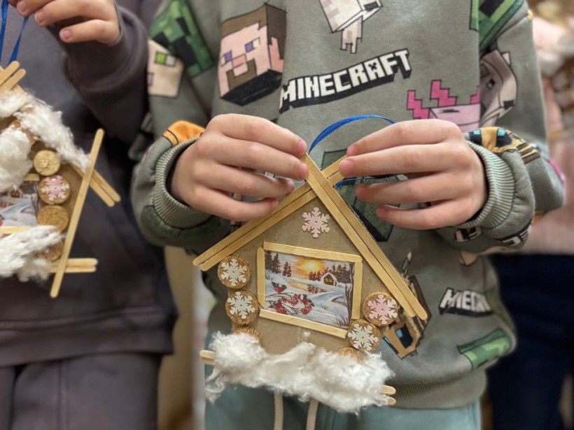 Дитина демонструє виготовлений на майстер-класі "Казковий будиночок"