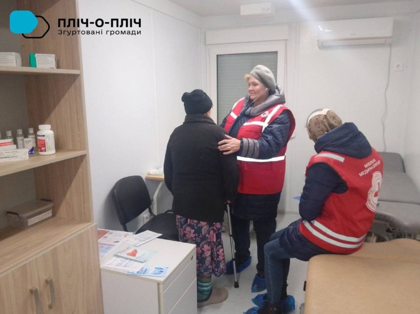 Фахівчиня Червоного Хреста проводить медичний огляд жінки похилого віку