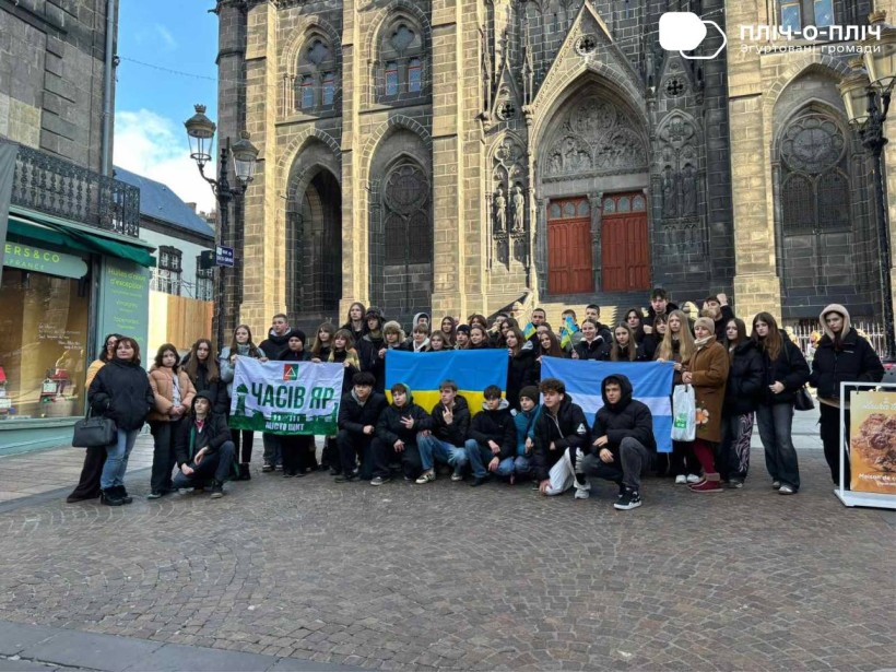 Діти з Часовоярської та Кременчуцької громад тримають прапори громад на площі у французькому місті