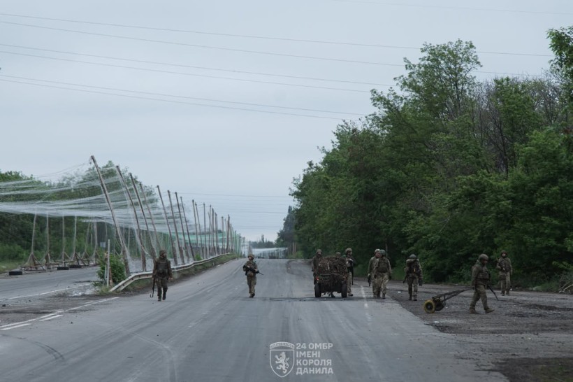 Військові йдуть до дорозі, накритої антидроновими сітками