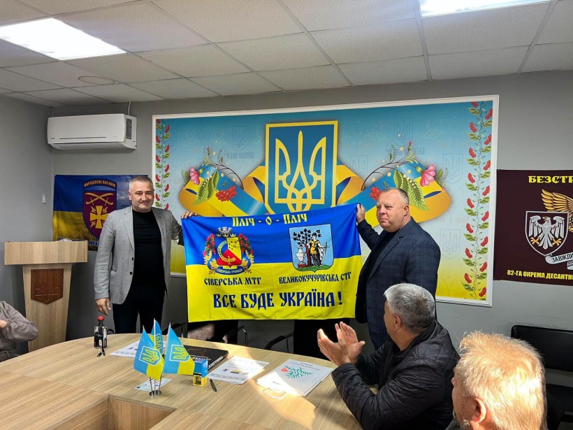Начальник Сіверської міської військової адміністрації Олексій Воробйов та Великокучурівський сільський голова Василь Тодеренчук тримають прапор з символікою порєкту та гербами громад
