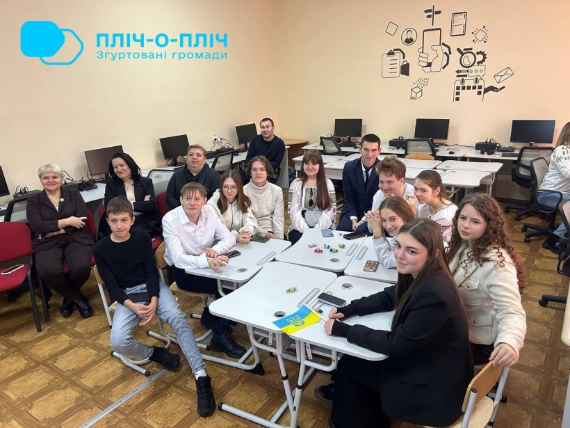 Учні сидять за білими партами та дивляться на екран монітора.