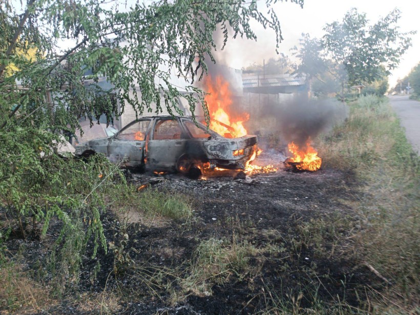 Автомобіль палає на узбіччі після ворожого обстрілу.