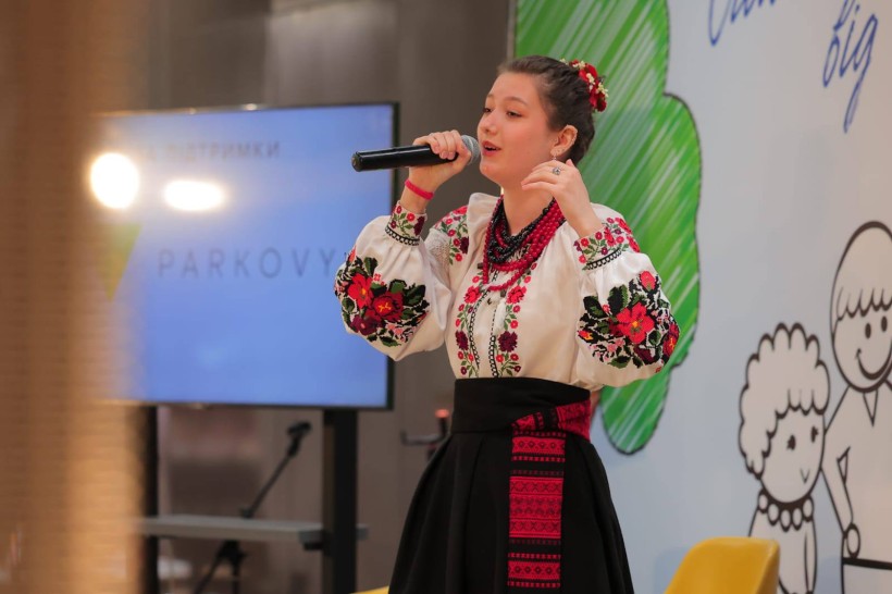 Дівчина у народному костюмі виконує пісню.