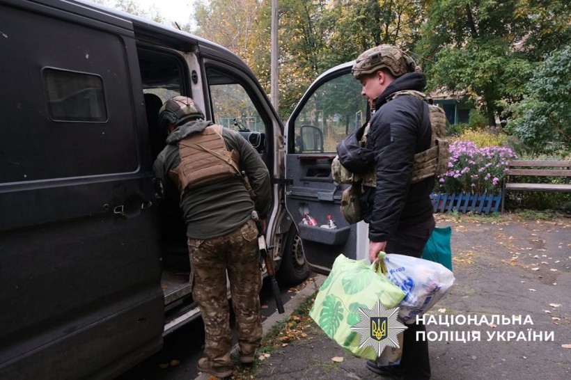 Полійейські допомагають людям занести речі в евакомобіль