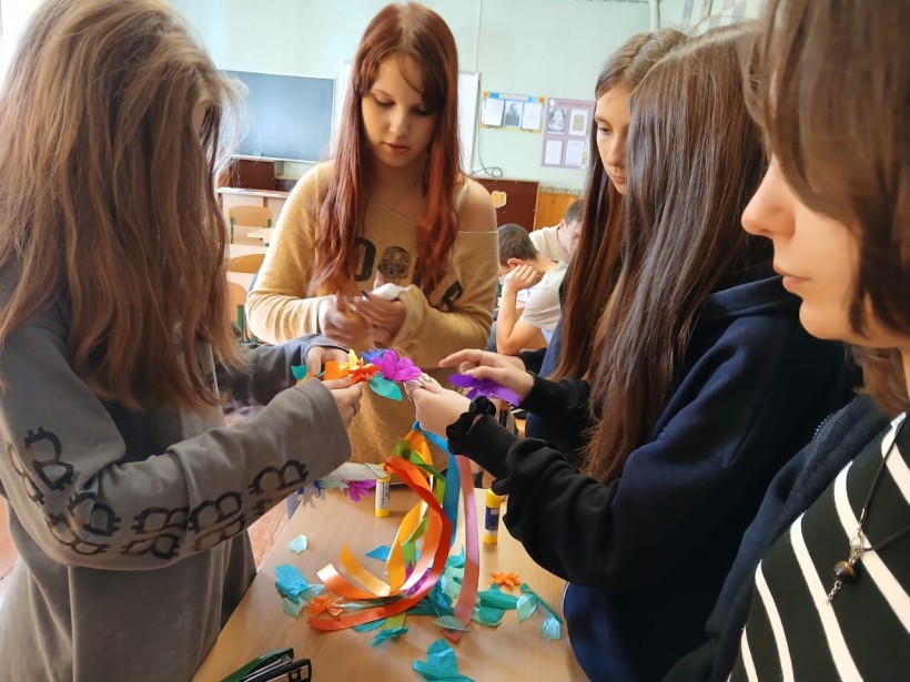 П'ятеро дівчат, які займаються виготовленням патріотичних сувенірів. У руках кожної - кольорові стрічки.
