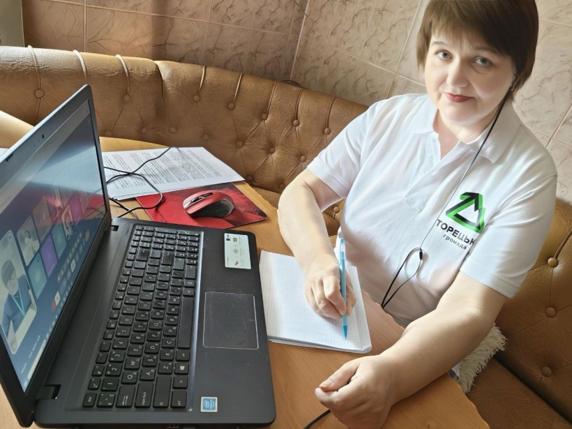 Фахівець військової адміністрації сидить за столом, слухаючи доповідачів на семінарі