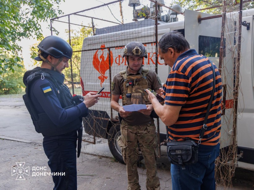 Рятувальники розмовляють з чоловіком поруч з евакомобілем