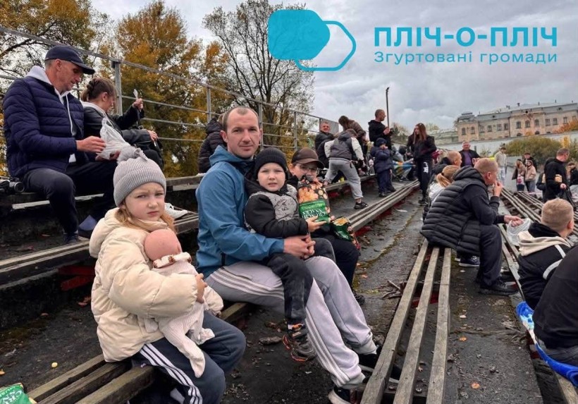 Глядачі на заході чидять на лавках