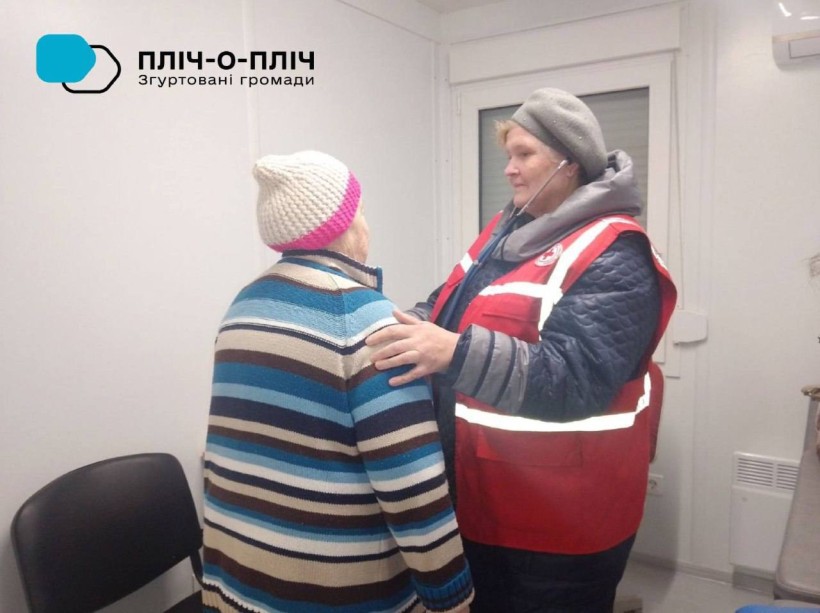 Фахівчиня Червоного Хреста проводить медичний огляд жінки похилого віку