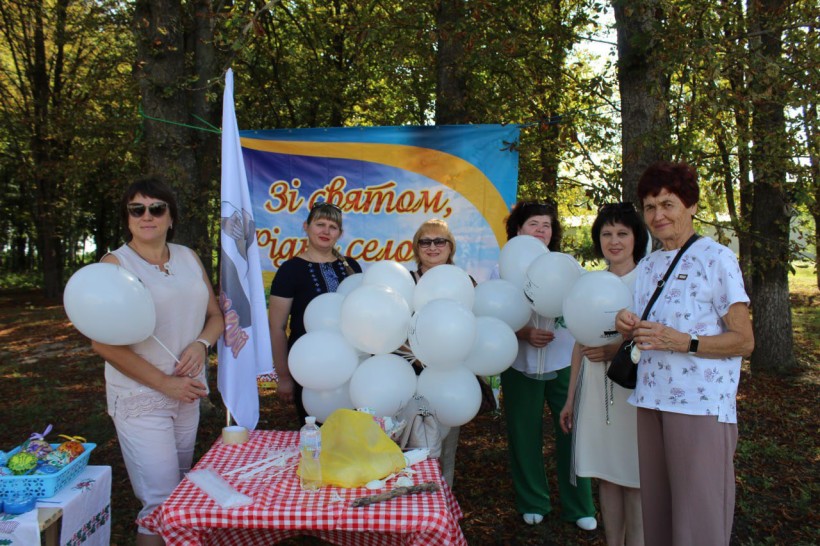 Фестиваль української культури «Смолянський куліш». Учасники фестивалю стоять біля банера з білими кульками.