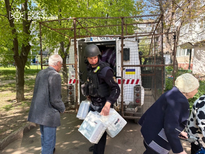 Рятувальники допомагають літнім людям сісти в евакуаційний автомобіль