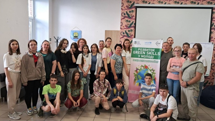 Спільне фото дітей, які беруть участь у екологічному проєкті «Розвиток GreenSkills у молоді». На задньому плані стоїть банер з надписом проєкту.
