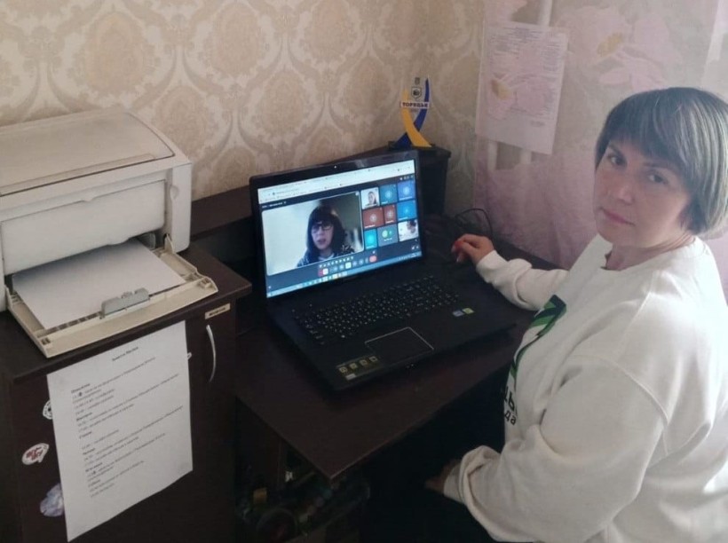 Представник військової адміністрації сидить за столом та слухає доповідача на семінарі