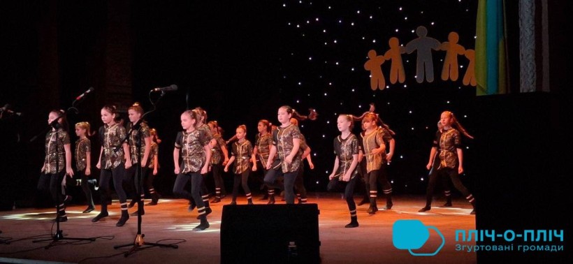 Молодіжний колектив на сцені у сценічному вбранні виконують танок.