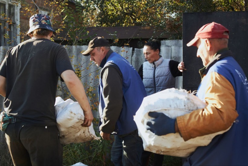 Волонтери допомагають людям вантажити твердопаливні брикети