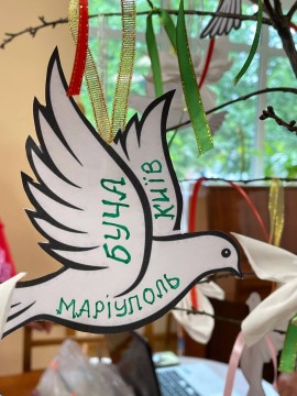 Білий паперовий голуб з назвами міст Буча, Київ, Маріуполь на крилах