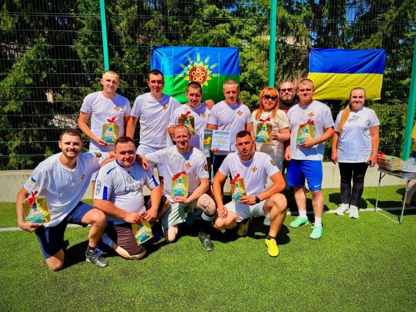 Спільне фото футбольної команди та представників влади. В руках тримають диплом та цінні призи з логотипом стели Донеччини.