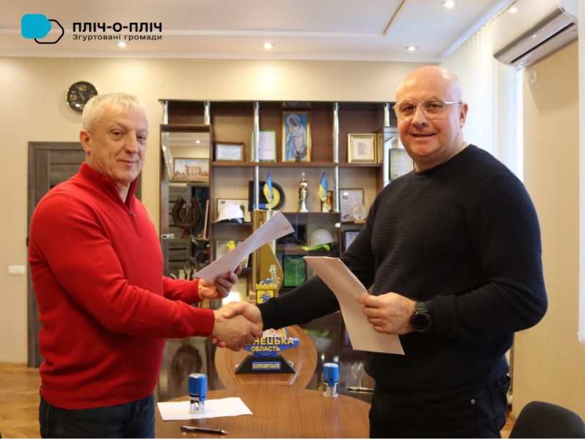 Очільники громад тримають підписаний меморандум та тиснуть руки