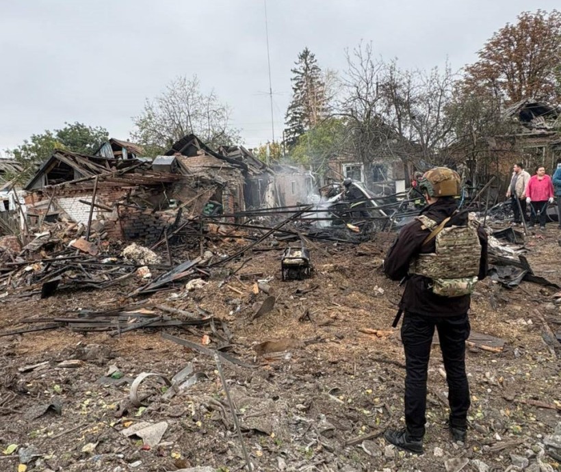 Зруйнований будинок після ворожого удару біля якого стоїть правоохоронець