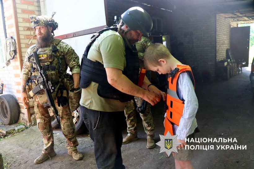 Поліцейський вдягає на хлопчика бронежилет