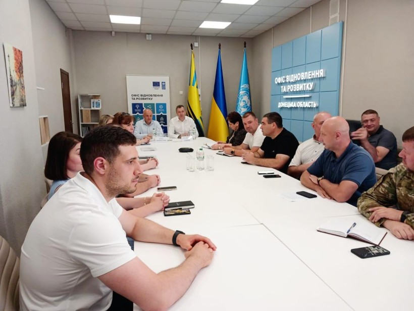 Учасники наради сидять за столом вся увага на центр стола, де стоять Юрій Винокуров та Владислав Лаврик.