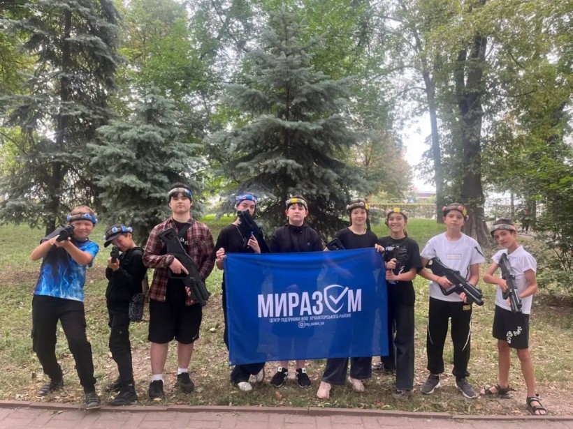 Учасники гри "Лазертаг" зі спорядженням тримають прапор Центру ВПО "Миразом"