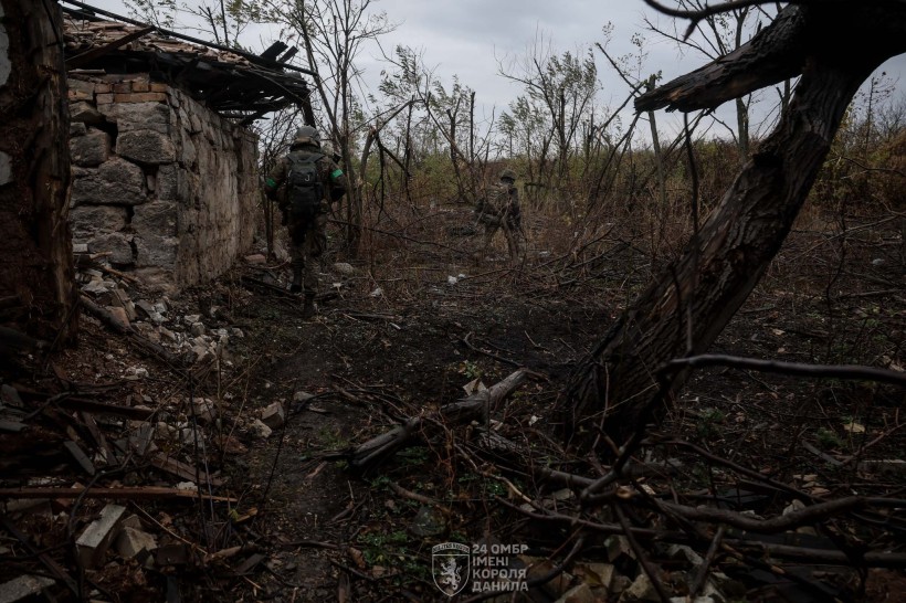 Двоє піхотинців з зеленими смужками на рукавах, обережно проходять скрізь розбиту будівлю та понівечені дерева.