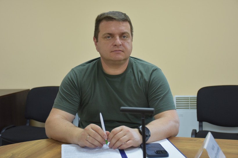 Директор департаменту агропромислового розвитку та земельних відносин Артем Чаган на нараді, сидить за столом, тримає ручку.