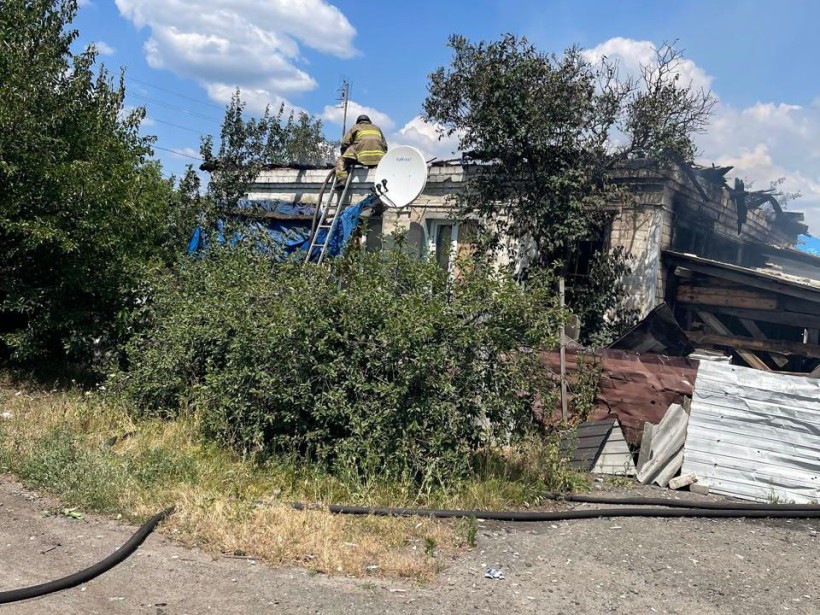 Рятувальники гасять пожежу всередині будинку, в якого згоріла покрівля після обстрілу окупантів.