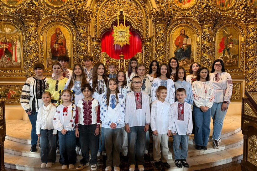 Групове фото дитячого хору у вишиванках біля позолоченого іконостаса в церкві