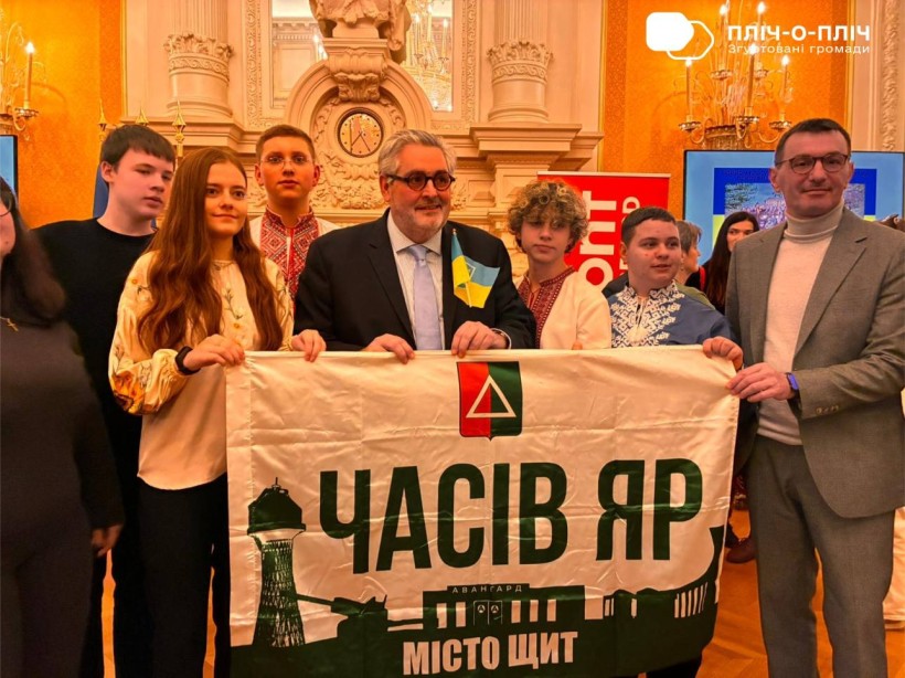 Мер французького міста тримає прапор Часового Яру, поруч стоять діти