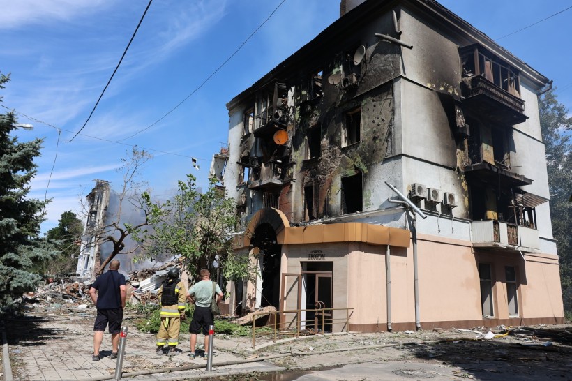 Люди стоять біля зруйнованого та обгорілого будинку в Краматорську